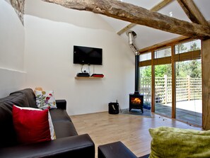 A modern living room with a sofa, a flat-screen TV, a fireplace, and a large window. - 2 bedroom accommodation in Umberleigh (Umberleigh)