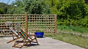 A wooden deck with a colorful striped chair and a blue planter. - 2 bedroom accommodation in Umberleigh (Umberleigh)