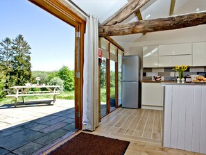 A kitchen with a refrigerator, a dining table, and a view of the outdoors.