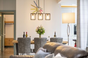 Un espace repas moderne avec une table en bois, des chaises à revêtement gris et une horloge murale décorative.