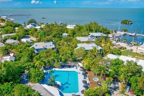 An aerial view of a resort with a central swimming pool, surrounded by lush greenery and multiple buildings. - 2BR Condo with Pool & Marina in Marathon (Marathon)