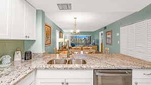 A kitchen with white cabinets, a granite countertop, a stainless steel sink, and a dishwasher. - 2BR Condo with Pool & Marina in Marathon (Marathon)