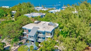 A coastal property with multiple buildings, a clear view of the ocean, and lush greenery. - 2BR Condo with Pool & Marina in Marathon (Marathon)