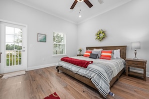 A bedroom with a bed, a nightstand, a window, and a door.