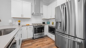 A modern kitchen with white cabinets, stainless steel appliances, and a wooden floor. - Looking for privacy minutes from 30A? Look no further! Come stay with us! (Santa Rosa Beach)