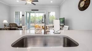 A modern kitchen with a stainless steel sink, a ceiling fan, and a clock on the wall. - Looking for privacy minutes from 30A? Look no further! Come stay with us! (Santa Rosa Beach)
