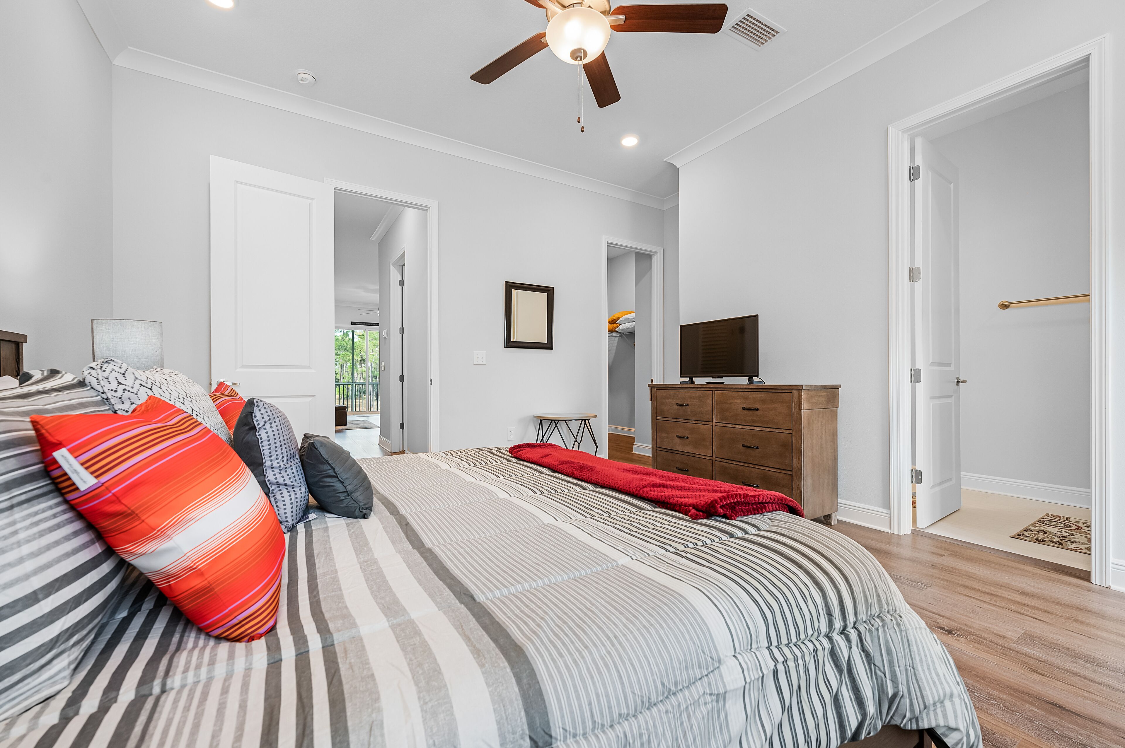 Une chambre à coucher avec un lit, un ventilateur de plafond, une commode et un téléviseur.