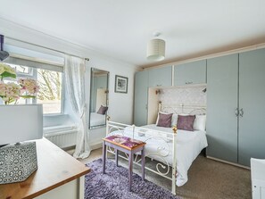 Ein Schlafzimmer mit Bett, Nachttisch, Spiegel und Kleiderschrank.