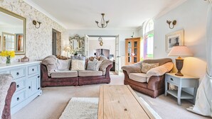 A living room with a sofa, a coffee table, a cabinet, a mirror, and a lamp. - The Old Farmhouse-UK12895 (Pelynt, near Looe)