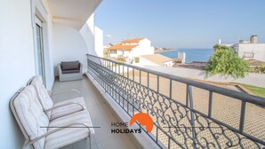 Ein Balkon mit Meerblick, ein weißes Gebäude und das Logo von "Home Holidays".