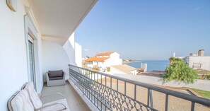 A balcony with a view of the sea, a white building, and a logo for "Home Holidays".