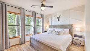 A bedroom with a large bed, a ceiling fan, a wall-mounted deer head decoration, and a nightstand with a lamp. - 'Foxtail' Cabin Retreat: Steps to Beaver Lake! (Rogers)