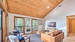 A spacious living room with a wooden ceiling, large windows, and a cozy seating area. - 'Foxtail' Cabin Retreat: Steps to Beaver Lake! (Rogers)