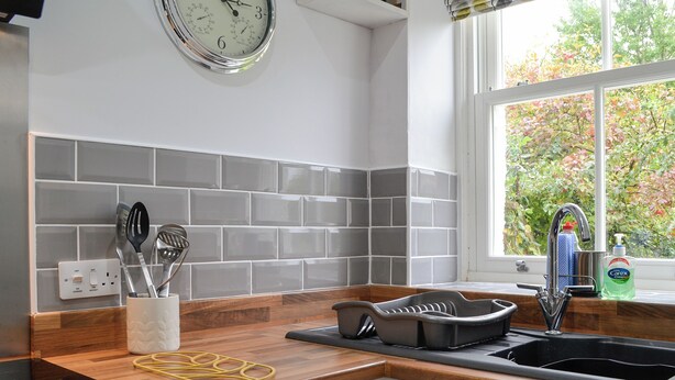 A modern kitchen with a wooden countertop, a black sink, and a window with a view of trees. - 2 bedroom accommodation in Hesket Newmarket, near Wigton (Hesket Newmarket, near Wigton)