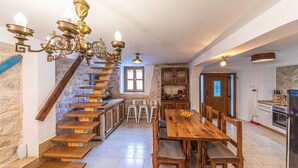 A kitchen with a wooden staircase, a dining table with chairs, and a chandelier. - Luxurious home in Okrug Gornji (Okrug Gornji)