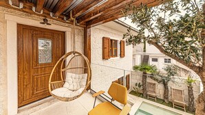 A balcony with a hanging chair, a yellow chair, and a pool. - Luxurious home in Okrug Gornji (Okrug Gornji)