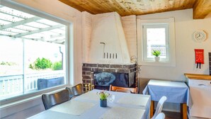 A dining area with a brick fireplace, a clock, and a fire blanket on the wall.