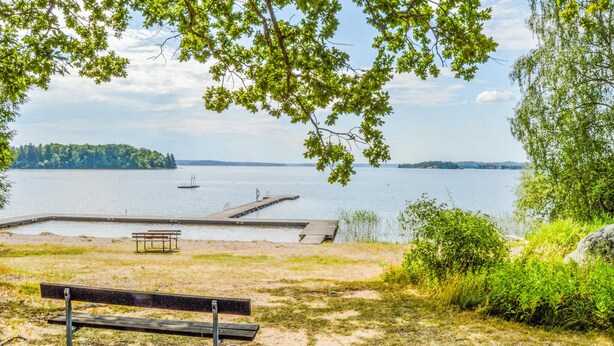 A lakeside park with a bench, a dock, and a distant island.