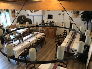 A dining area with round tables, candles, and a rustic stone wall.