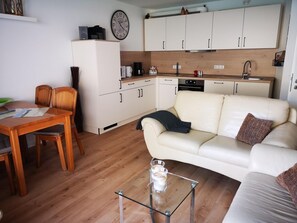 A compact living space with a dining area, a sofa, and a kitchenette.