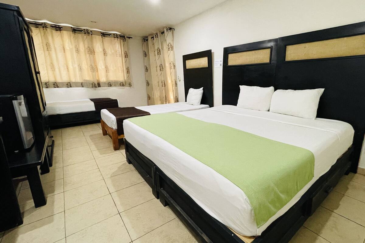 A hotel room with two beds, a desk, a chair, and a TV.