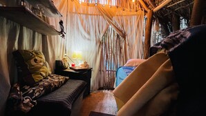 Una habitación acogedora con cama, una silla, una mesita de noche con lámpara y una ventana con cortinas.