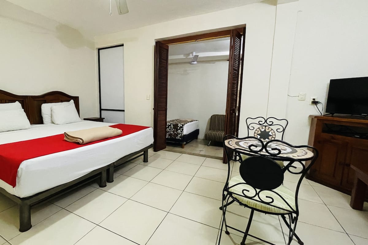 A hotel room with a bed, a chair, a TV, and a wardrobe.