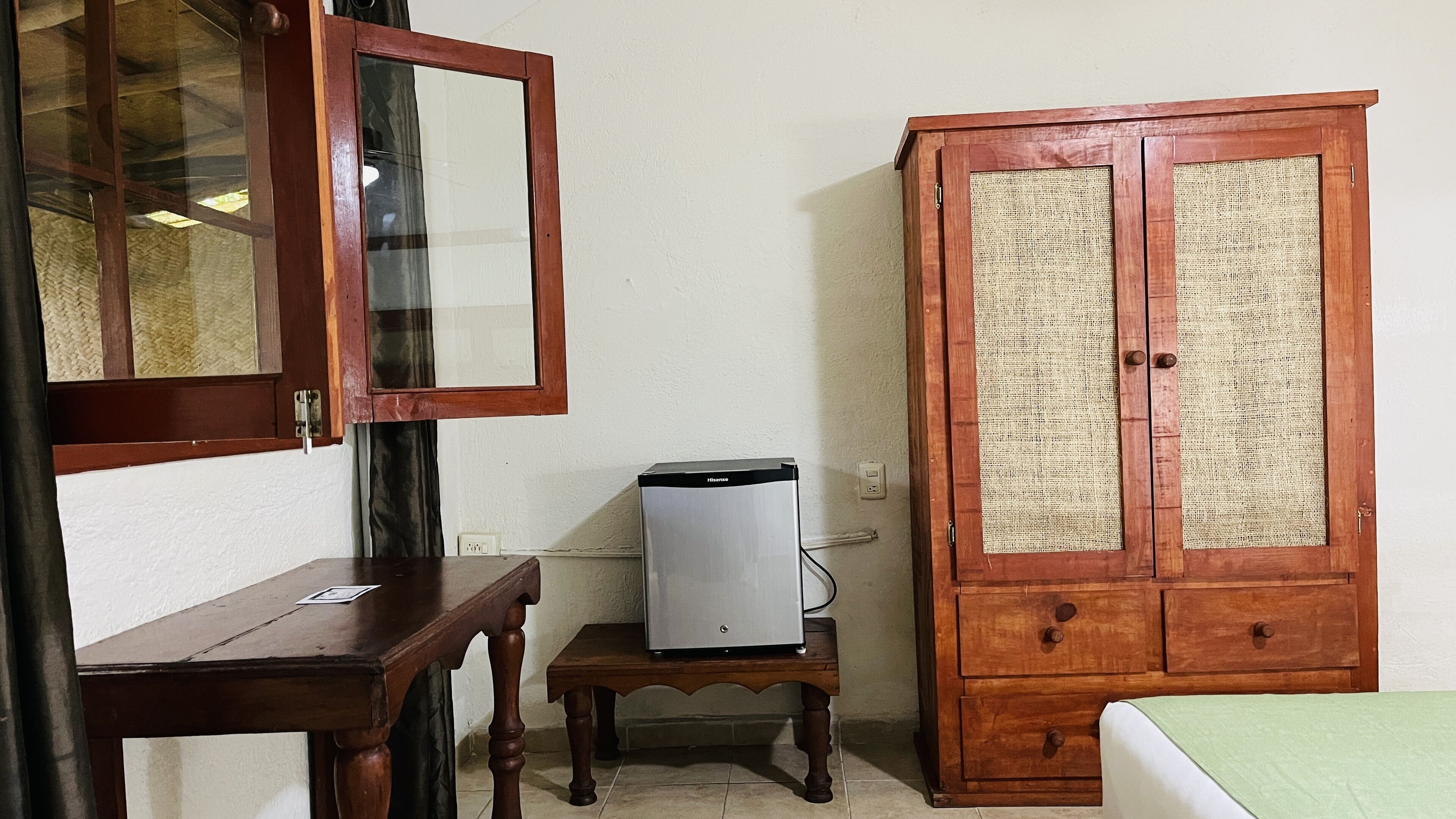 Une pièce comprenant un meuble en bois, une petite table et un réfrigérateur.