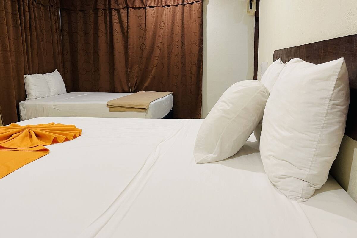 A hotel room with a bed, a small sofa, and a nightstand.