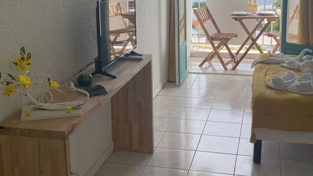 Ein Zimmer mit Schreibtisch, Bett, Meerblick und einem Balkon mit Stühlen und Tisch.