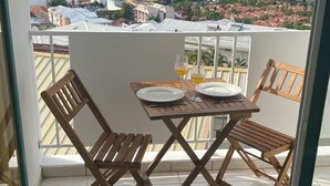 Ein Balkon mit Tisch und Stühlen mit Blick auf eine Küstenstadt, einschließlich Boote und Gebäude.