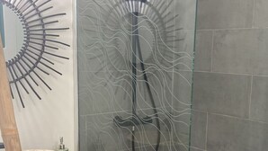 Ein modernes Badezimmer mit Duschkabine aus Glas, einem Holzlagerflanschrank mit Waschbecken und einer Metall-Kaffeekanne.