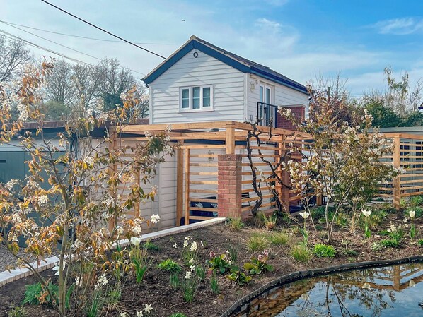 A house with a wooden fence, garden, and a small pond.