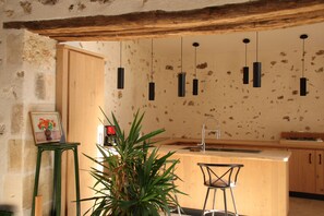 Eine Küche mit einer Holztheke, Pendelleuchten und einem Blumentopf.