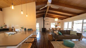 A modern kitchen with a central island, wooden flooring, and a ceiling fan. - Relax in this boho coastal home walking distance to beautiful beach (Blairgowrie)