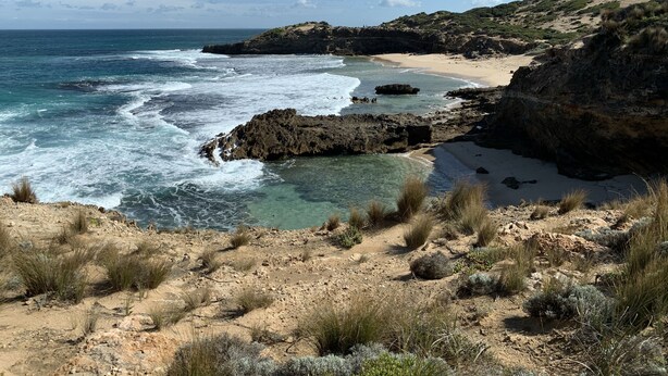 A coastal landscape with rocky terrain, clear blue water, and a sandy beach. - Relax in this boho coastal home walking distance to beautiful beach (Blairgowrie)