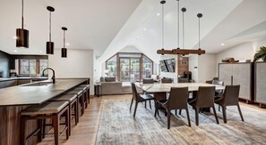 A modern kitchen with a long island, bar stools, and pendant lighting. - Valley View Residence with Access to Pool (Vail)