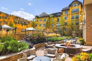 A hotel courtyard with outdoor seating, a fire pit, and a mountain backdrop. - Valley View Residence with Access to Pool (Vail)