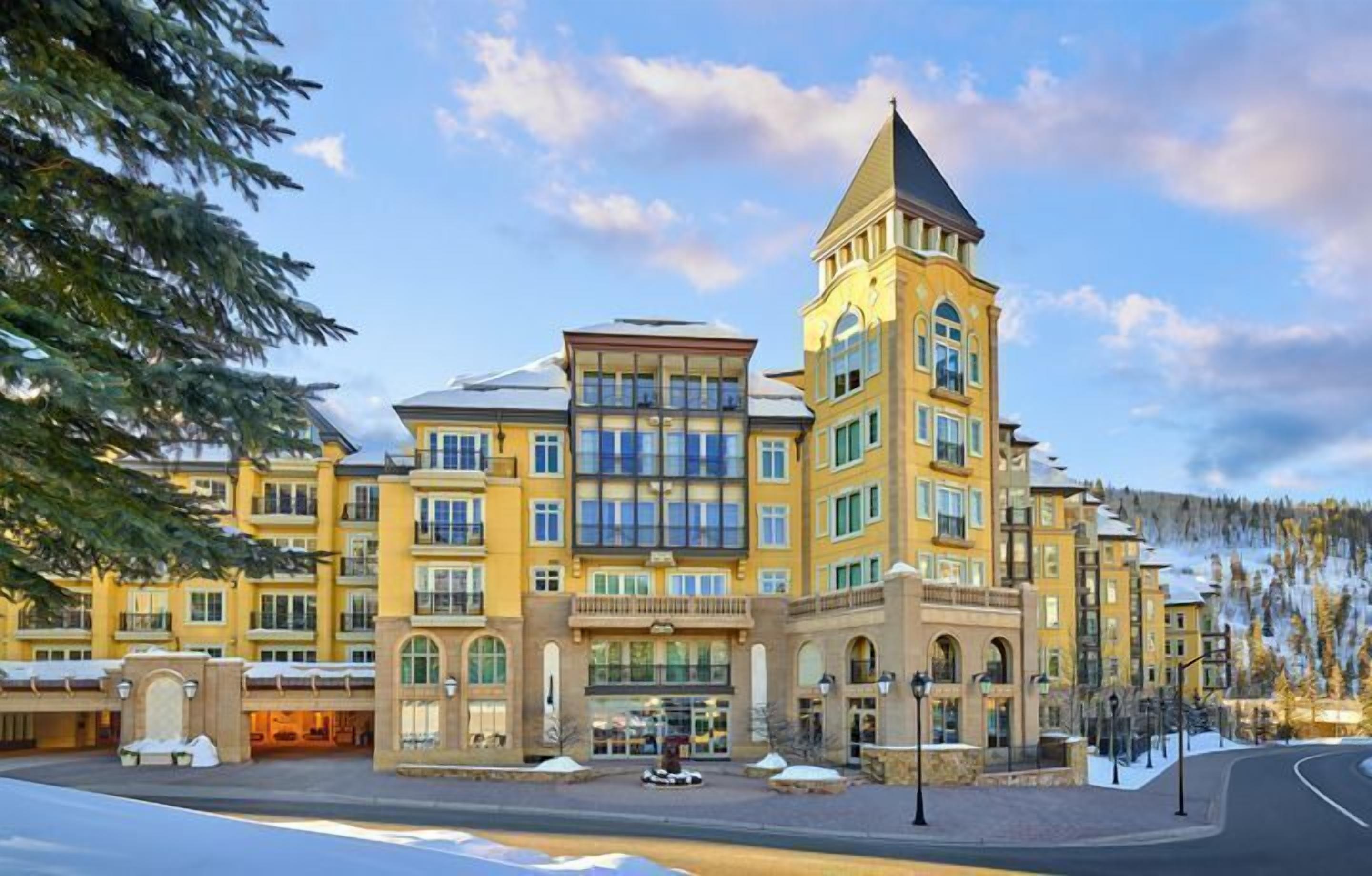 A multi-story hotel with a central tower, large windows, and a snow-covered landscape.