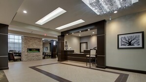 Eine großzügige Lobby mit einer Rezeption, einer Sitzecke und einem Kamin aus Stein.