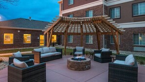 An outdoor seating area with wicker furniture and a central fire pit.