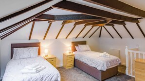 Ein Schlafzimmer mit zwei Betten, Holzbalken und einer weißen Treppe.