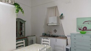 A compact kitchen with a dining table, chairs, a stove, and a small cabinet. - Sandra's House in Meta di Sorrento (Meta)