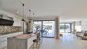 Et moderne køkken med en central ø, barstole og et spiseområde med udsigt over byen.