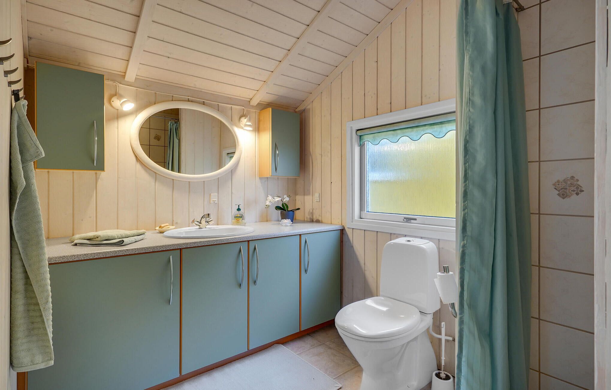 A bathroom with a toilet, sink, and mirror.