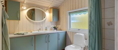 A bathroom with a toilet, sink, and mirror.