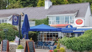 Un pub tradizionale con posti a sedere all'aperto, una targa e un giardino curato.