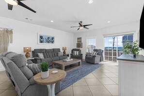 A spacious living room with a gray sofa set, a wooden coffee table, and a ceiling fan. - Five Bed Condo with Peekaboo Ocean Views & Pool Steps to Sand!  (North Myrtle Beach)