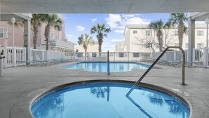 Ein Poolbereich mit zwei runden Pools, umgeben von Palmen und einem weißen Zaun.