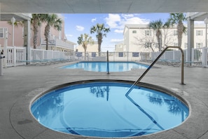 Ein Poolbereich mit zwei runden Pools, umgeben von Palmen und einem weißen Zaun.